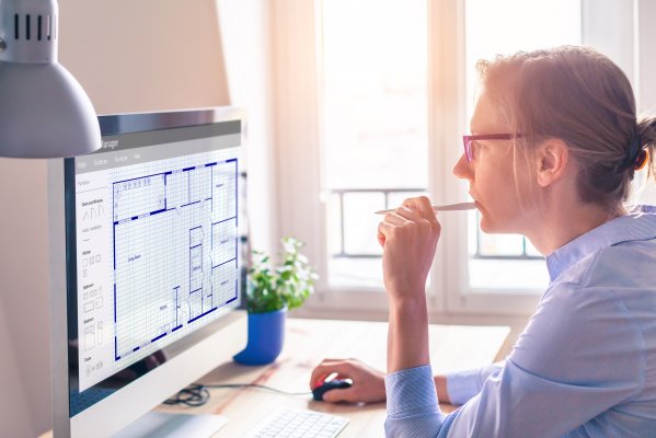 woman looking at computer screen with blueprints 
